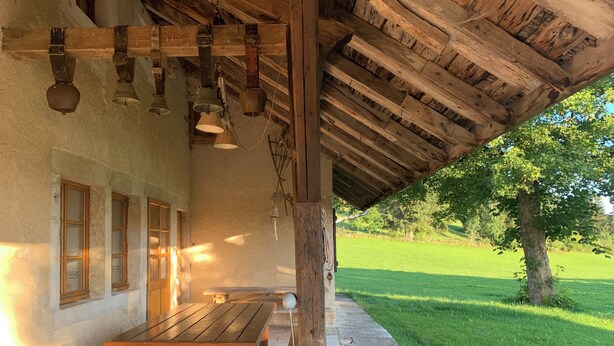 Un bâtiment rustique en bois doté d’un patio couvert, comprenant des bancs et une table.
