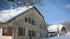 Un bâtiment en pierre doté de nombreuses fenêtres et dont le toit est recouvert de neige.