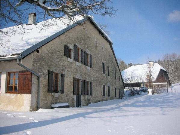 Un bâtiment en pierre doté de nombreuses fenêtres et dont le toit est recouvert de neige.