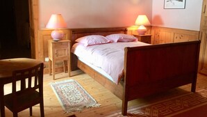 Une chambre confortable avec un lit en bois, deux tables de chevet avec des lampes, une chaise et un tapis sur le sol.