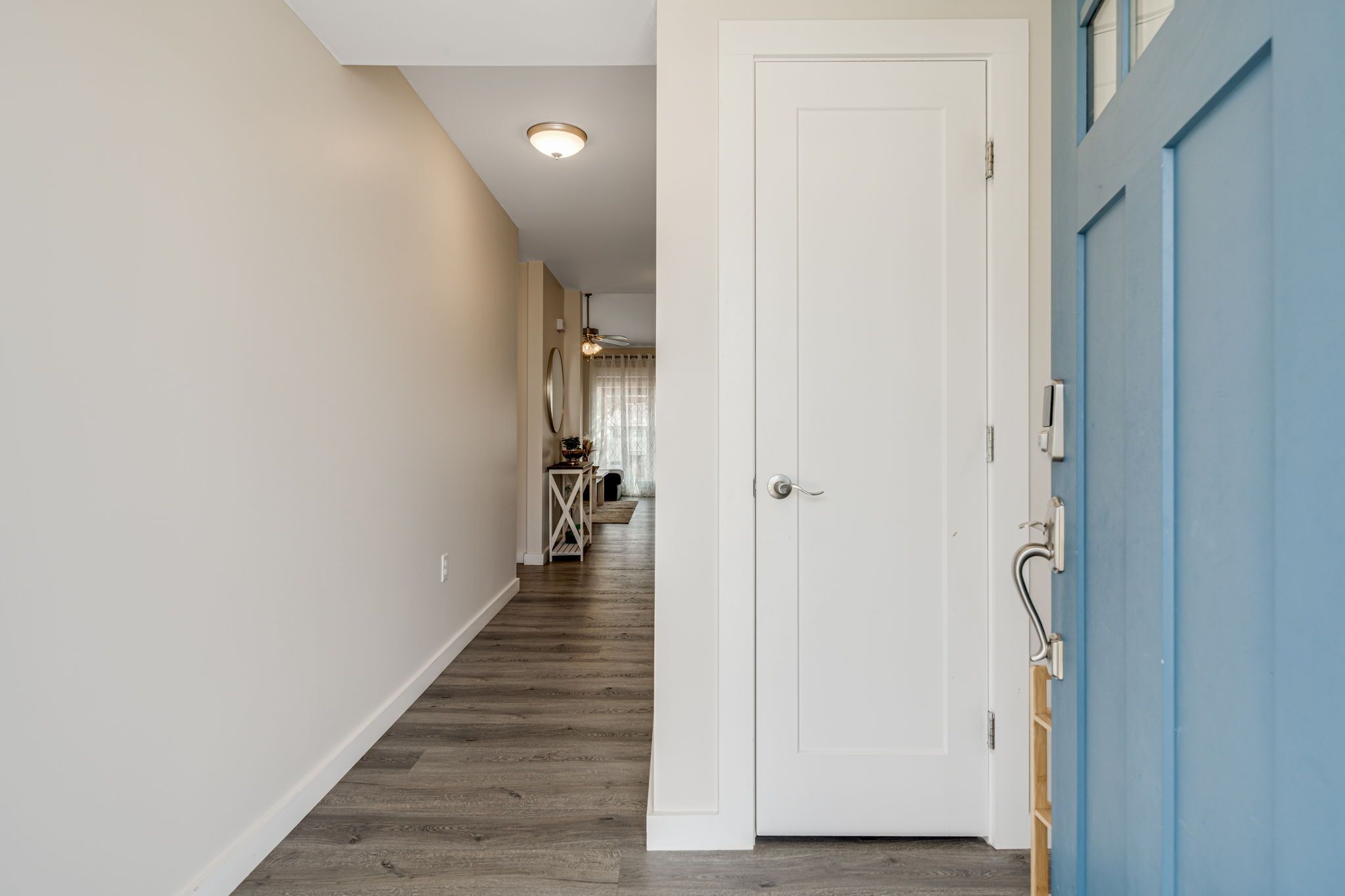 A hallway with a white door, a blue door, and a ceiling light.
