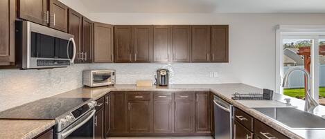 Une cuisine moderne avec des meubles en bois foncé, des appareils électroménagers en acier inoxydable et un dosseret carrelé.