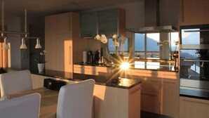 A modern kitchen with a central island, pendant lighting, and a view of the outdoors.