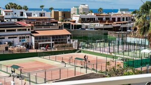 A tennis court with a net, surrounded by buildings and palm trees. - Modern studio with ocean views and heated pool in Malibu Park (San Eugenio Alto)