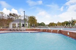 Une piscine avec des chaises longues et un kiosque.