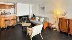 A modern living room with a fireplace, a sofa, a coffee table, and a bar area with stools.