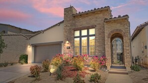 A residential house with a stone facade, a garage, and a well-maintained front yard with flowering plants. - 2BR retreat - hot tub, gym & Coachella nearby (La Quinta)