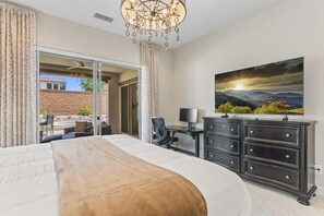 A bedroom with a large bed, a desk, a chair, a dresser, and a painting on the wall.