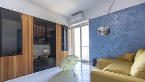 A modern living room with a yellow sofa, a glass umbrella, and a blue accent wall. - Seaview Cocò Home Piano di Sorrento SEA FRONT and FREE PARKING (Piano di Sorrento)