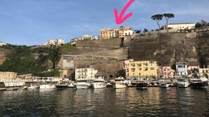 A coastal marina with boats docked, buildings on a cliff, and a clear sky. - Seaview Cocò Home Piano di Sorrento SEA FRONT and FREE PARKING (Piano di Sorrento)