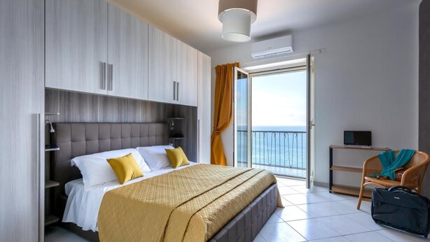A modern hotel room with a large bed, a balcony with a view, and a TV on a small table. - Seaview Cocò Home Piano di Sorrento SEA FRONT and FREE PARKING (Piano di Sorrento)