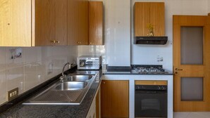 A modern kitchen with wooden cabinets, stainless steel appliances, and a black range hood. - Seaview Cocò Home Piano di Sorrento SEA FRONT and FREE PARKING (Piano di Sorrento)