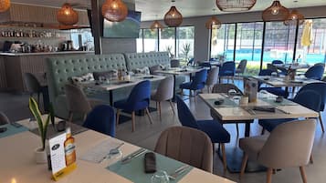 Un restaurant amb zona de bar, seients i un gran finestral que ofereix vistes a l'exterior.