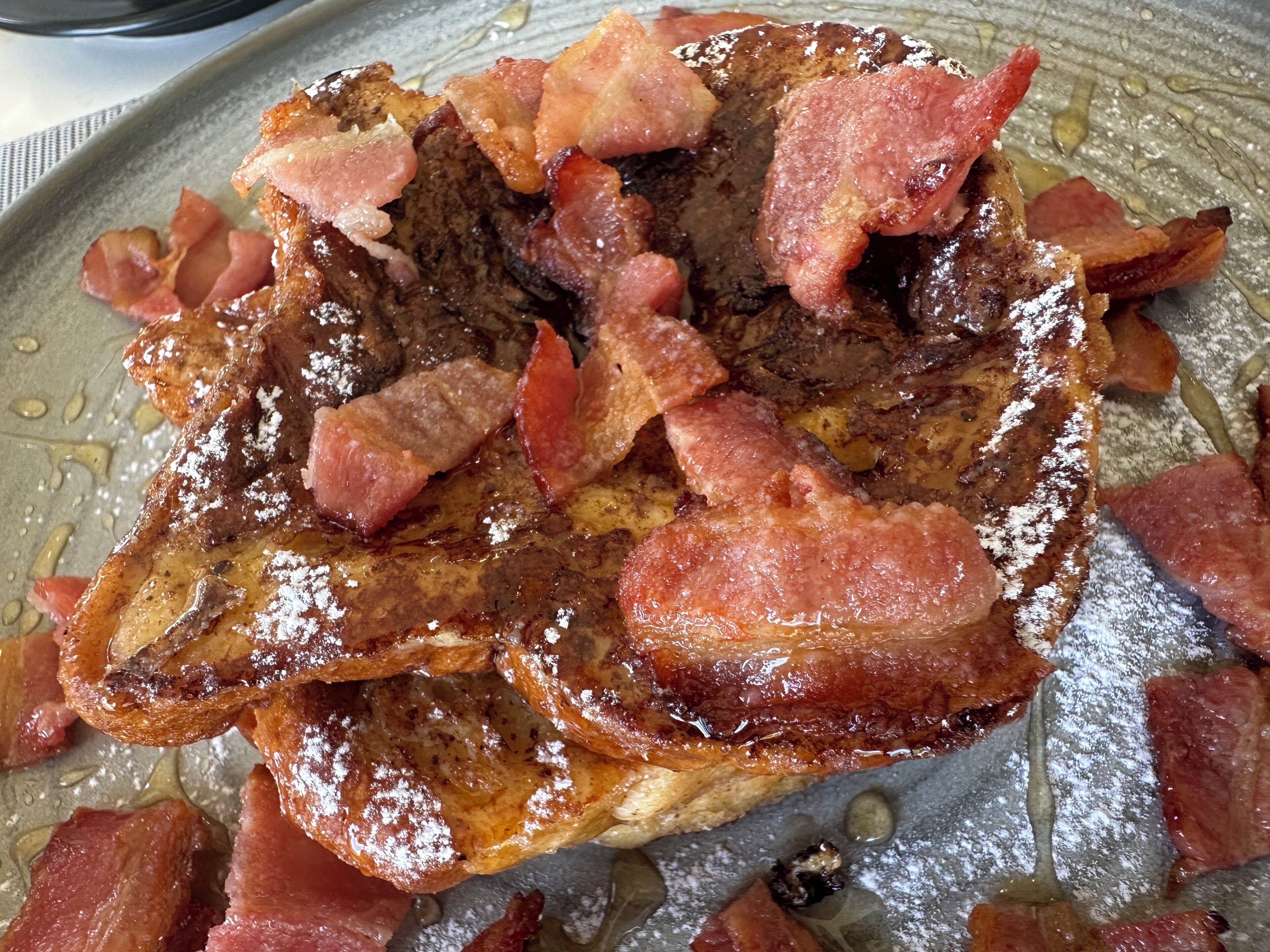 Un piatto per la colazione con pane tostato, pancetta e sciroppo.