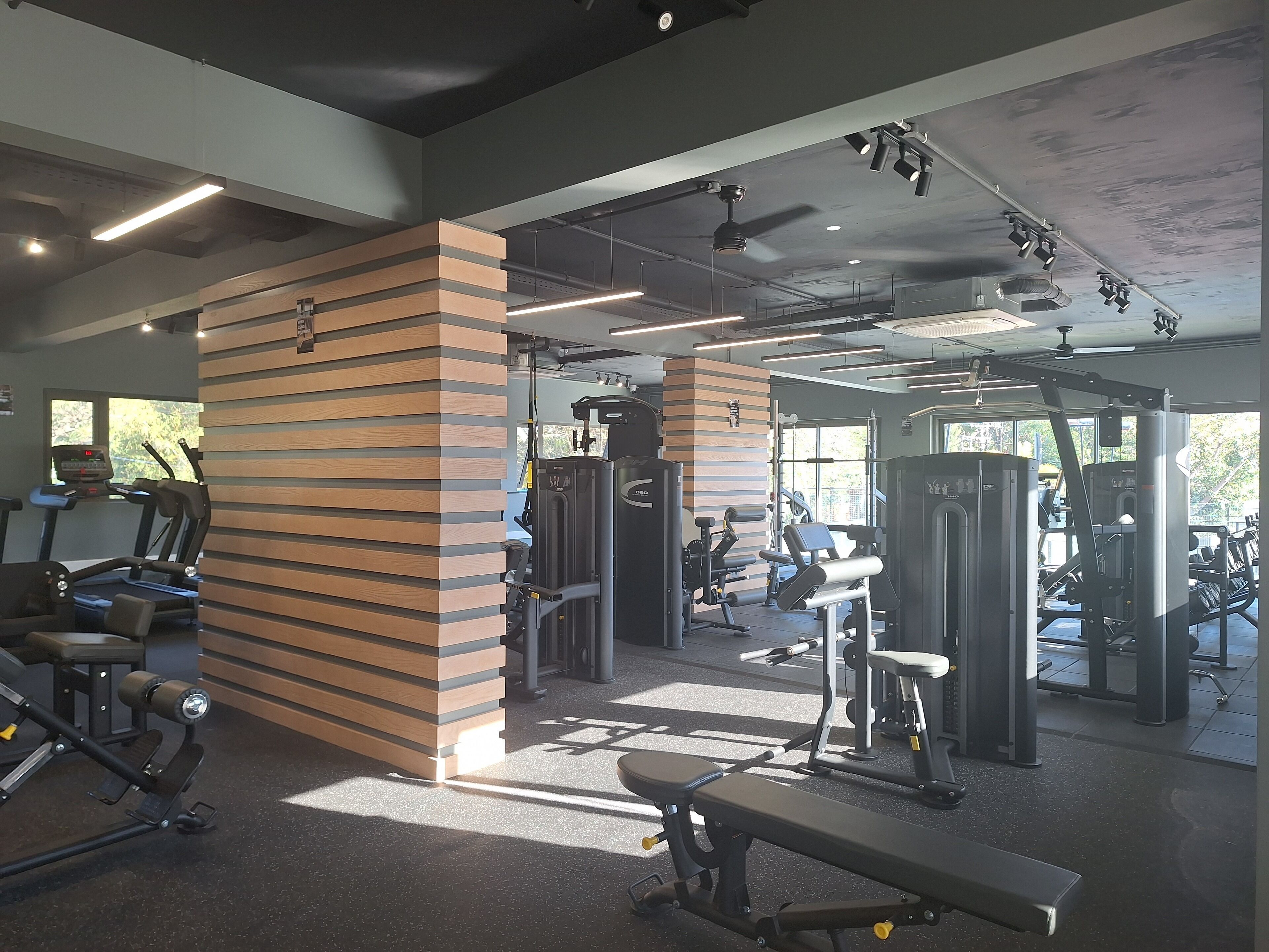 Un gimnasio con cintas de correr, máquinas de pesas y una banca.