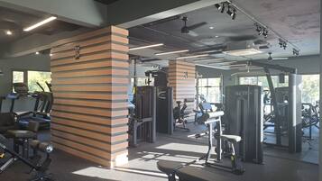 Un gimnasio con cintas de correr, máquinas de pesas y una banca.