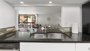 Una cocina moderna con un lavamanos doble, electrodomésticos de acero inoxidable y vistas a un comedor.