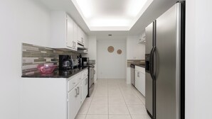 Una cocina moderna con armarios blancos, un refrigerador de acero inoxidable y un tragaluz.