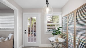 A room with a white door, a window with blinds, a table with a potted plant, and a wooden slat wall. - At Home in Acworth! (Acworth)