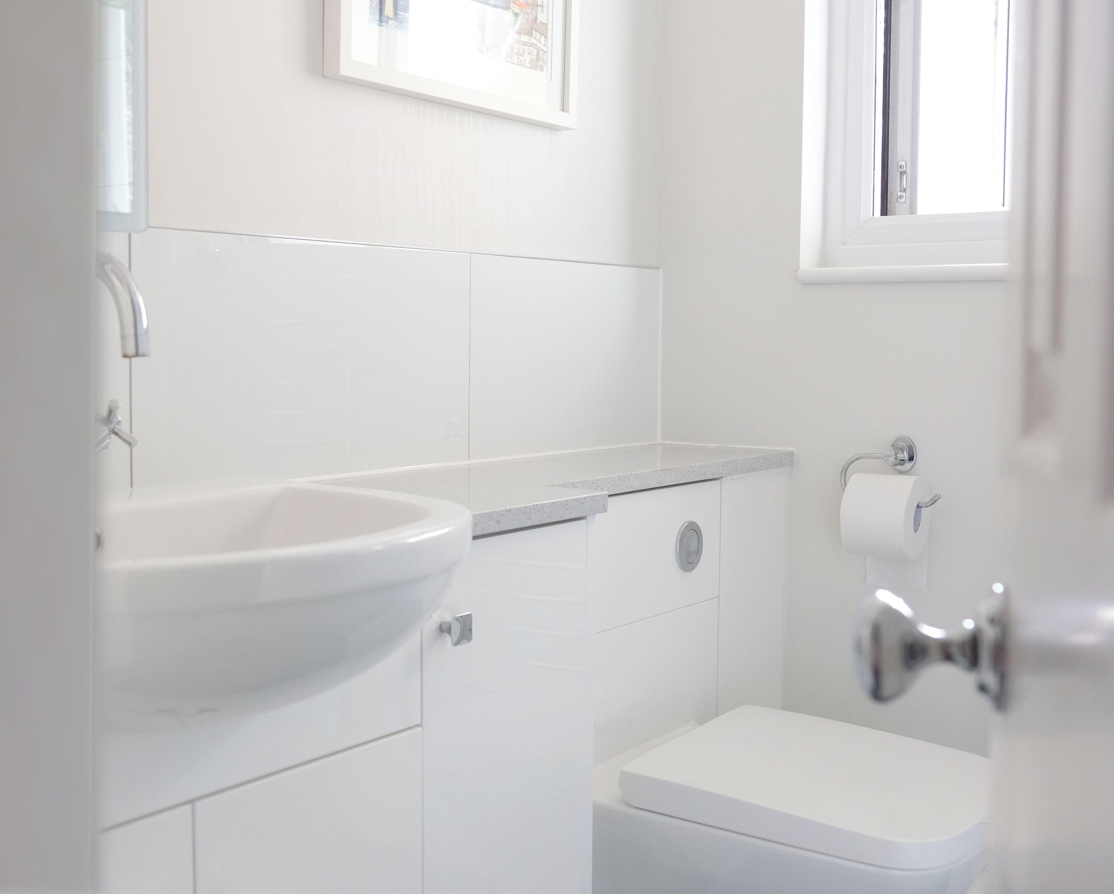 A bathroom with a white sink, toilet, and a window.