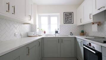 A modern kitchen with white cabinetry, a herringbone tile backsplash, a window, and a kitchen island.