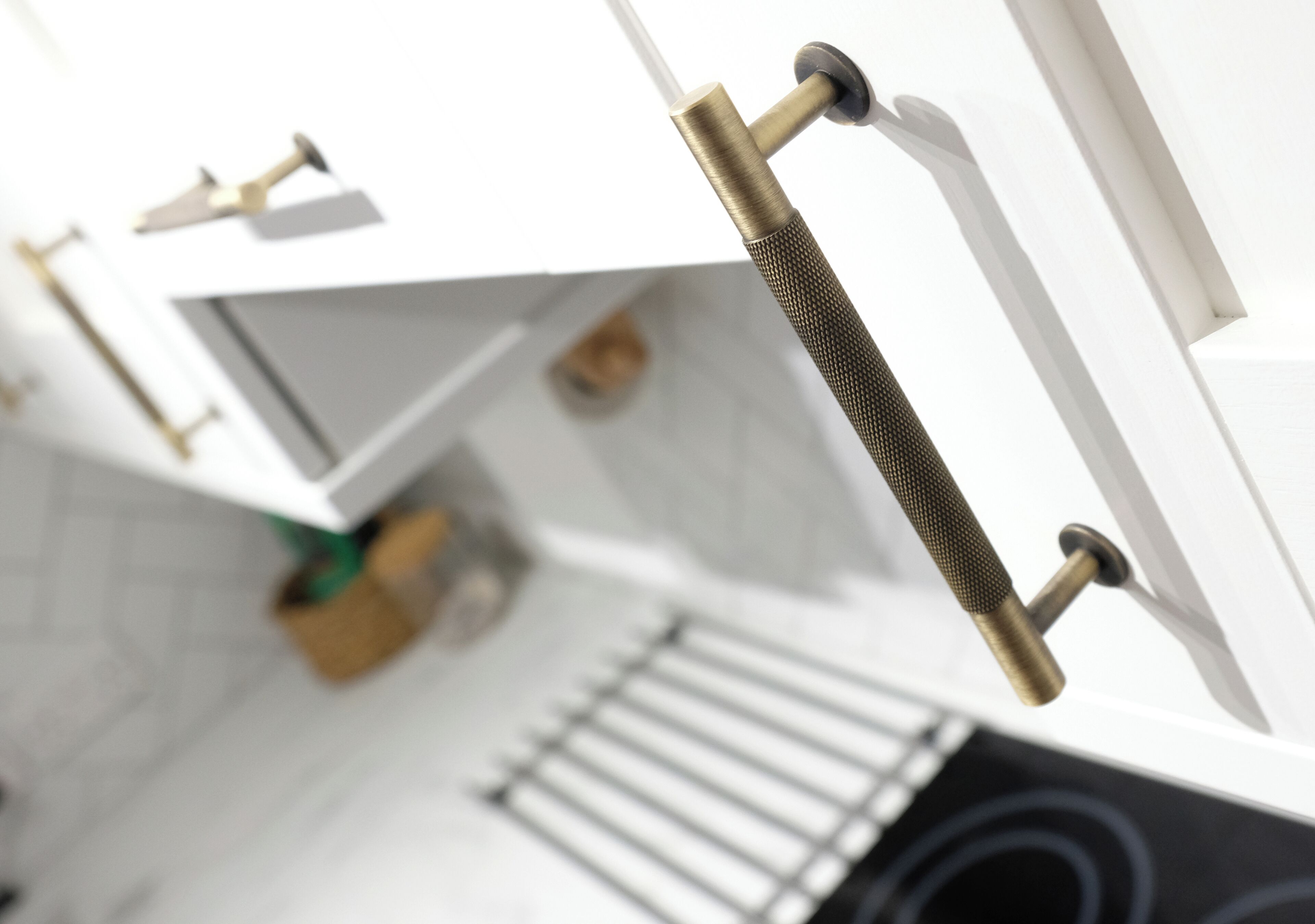 A close-up of a metallic handle with a textured grip, part of a white door or cabinet.
