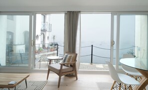Ein Balkon mit Blick auf das Meer und Boote, inklusive Stuhl, Tisch und Geländer.