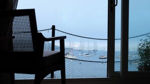 Udsigt fra et værelse med balkon med wirehegn over en lysthavn med flere sejlbåde.