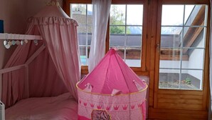 Una camera da letto con un letto a castello, un letto a baldacchino rosa e un tendone da gioco rosa.
