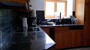Una cucina con un piano di lavoro nero, mobili in legno, una macchina per il caffè e una finestra.