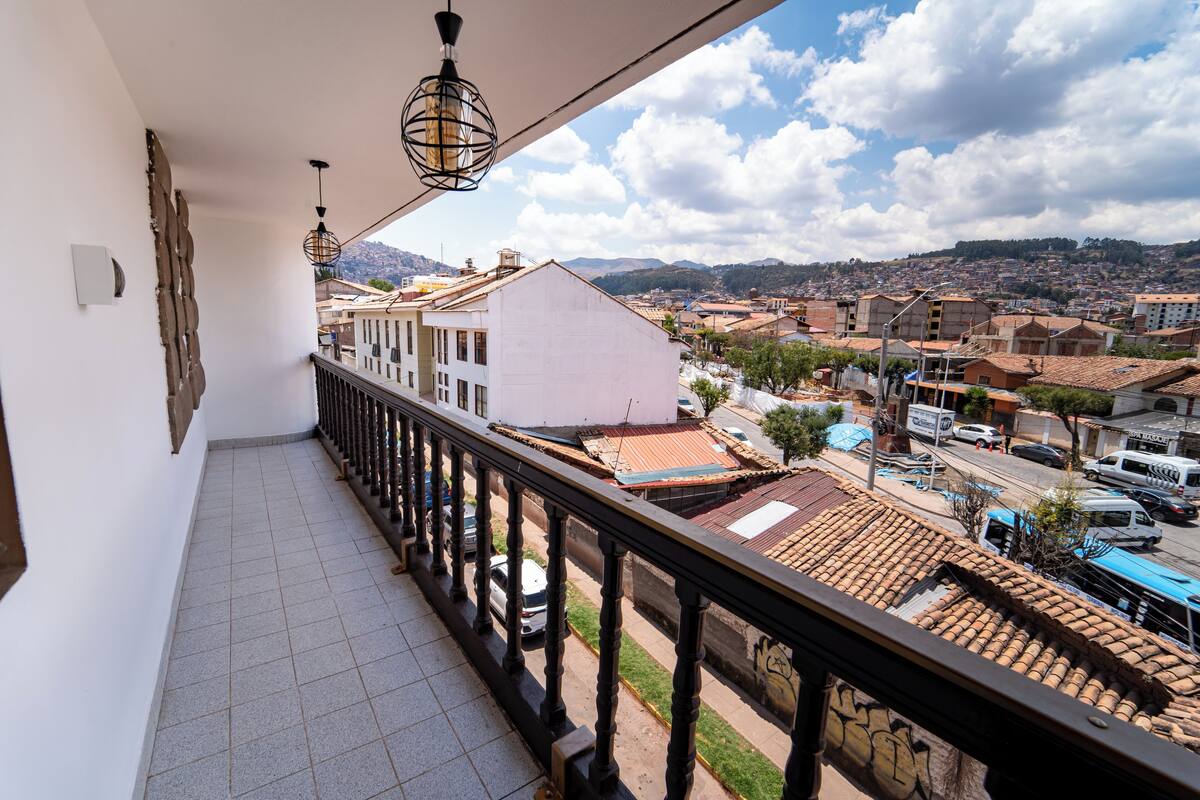 A balcony with a tiled floor, a railing, and hanging light fixtures.