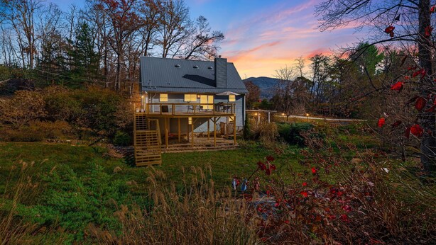 Una casa moderna con una amplia terraza, rodeada por un paisaje natural y árboles.