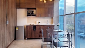 Une cuisine moderne avec des meubles en bois, un réfrigérateur en acier inoxydable, un four à micro-ondes et un coin repas comprenant une table et des chaises.