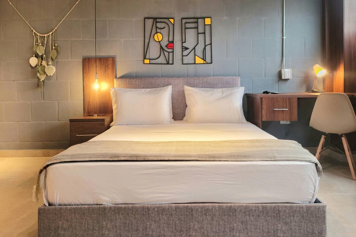 A modern bedroom with a large bed, bedside tables, a desk, and a chair.