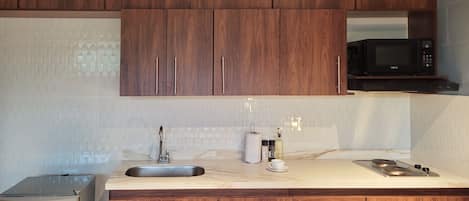 Une cuisine avec des meubles de rangement en bois, un évier en acier inoxydable, un four à micro-ondes et une cuisinière.