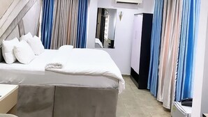 Ein modernes Hotelzimmer mit einem großen Bett, einem Schreibtisch und einem Kleiderschrank.