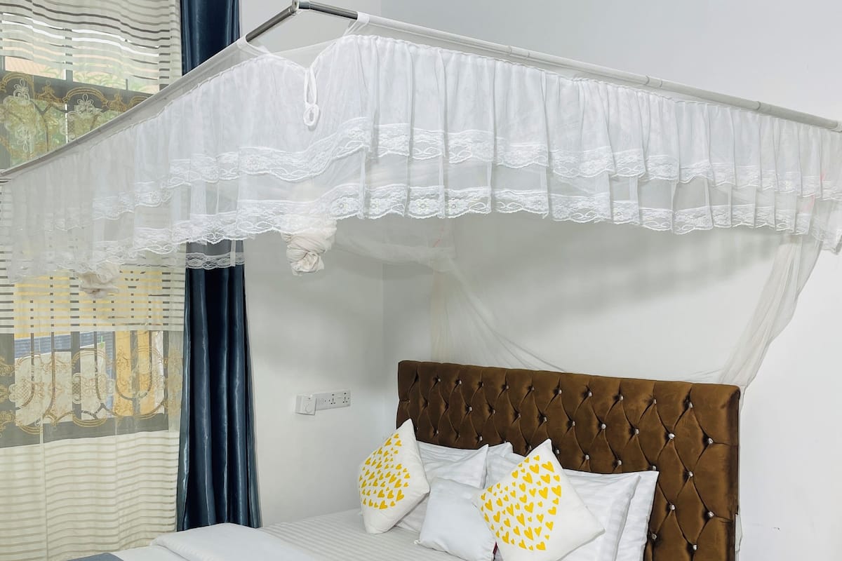 A neatly made bed with white and blue bedding, a brown headboard, and decorative pillows.