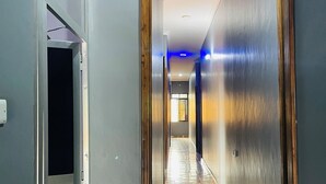 A hallway with a tiled floor, wooden paneling, and a door on the left. - KDP LODGE KIHONDA (Morogoro)
