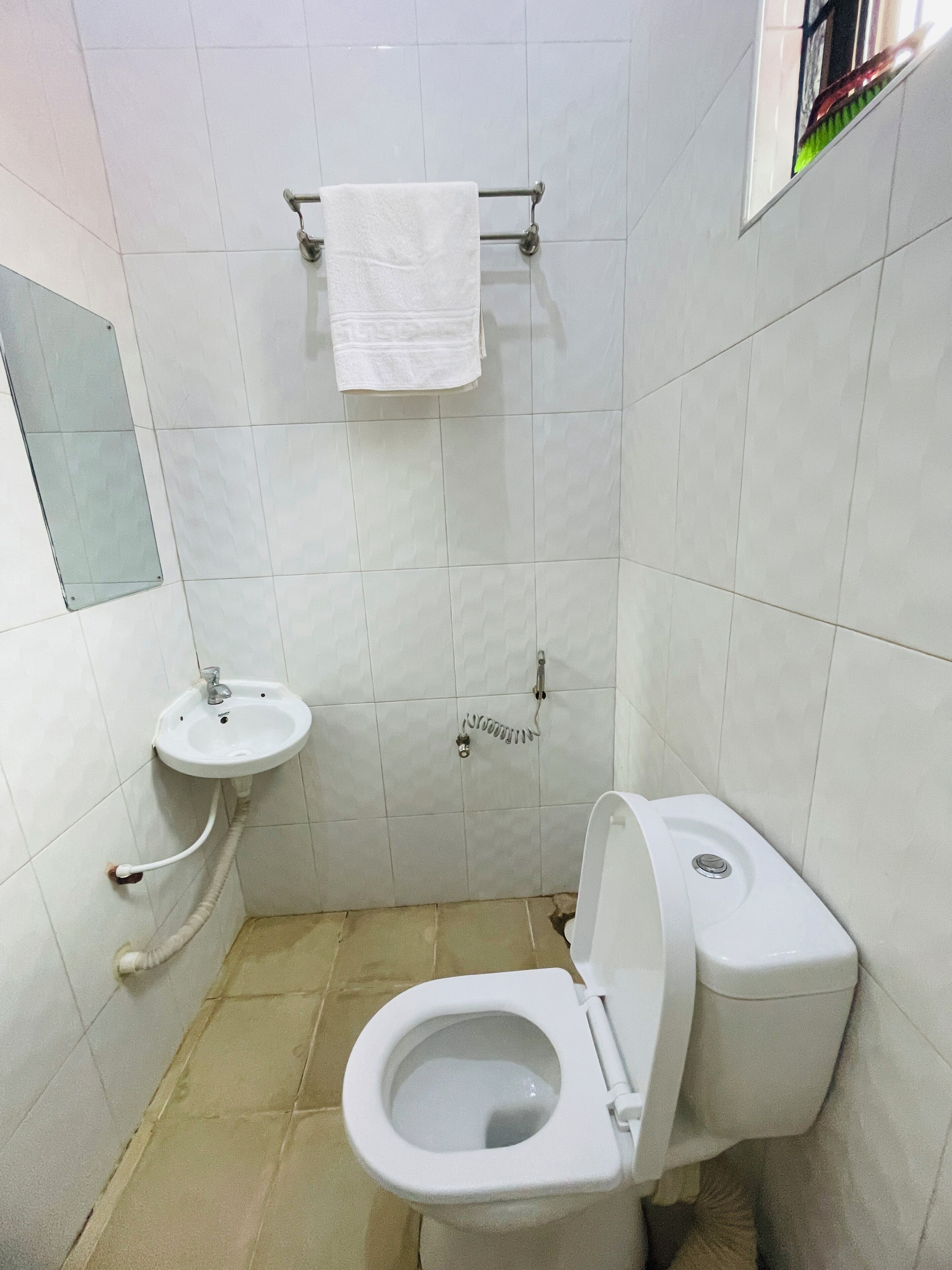 Une petite salle de bain propre, équipée de toilettes, d’un lavabo et d’un porte-serviettes.