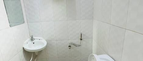 Une petite salle de bain propre, équipée de toilettes, d’un lavabo et d’un porte-serviettes.