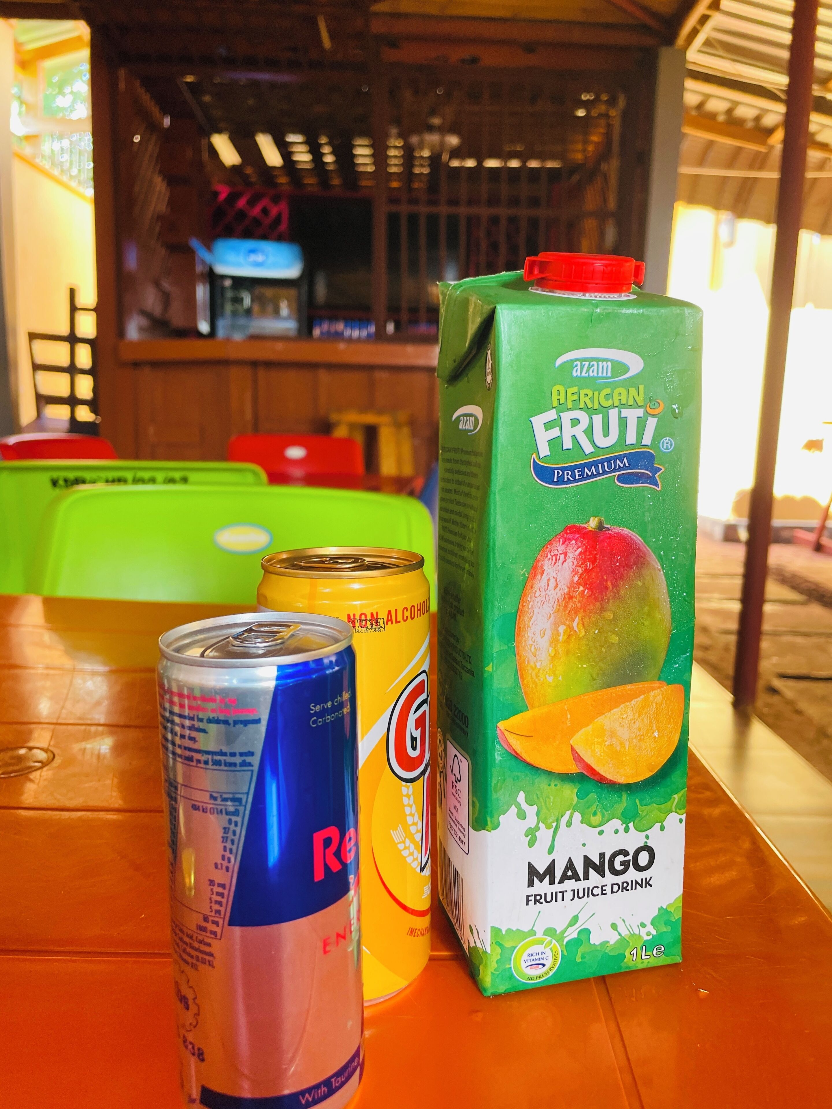 A table with a can of Red Bull, a can of Gatorade, and a carton of Mango Fruit Juice.