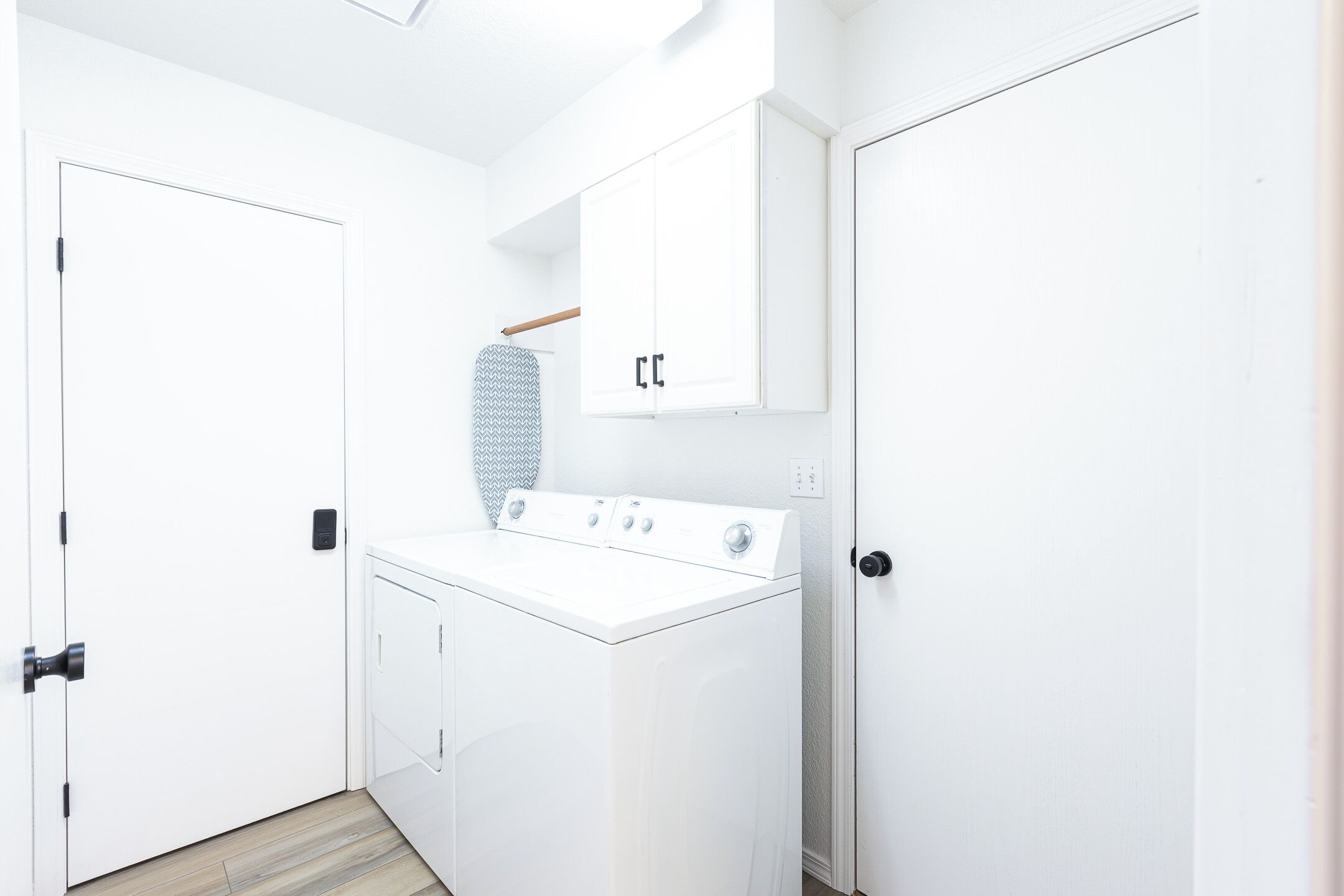 A laundry room with a white washing machine, a drying rack, and a cabinet.