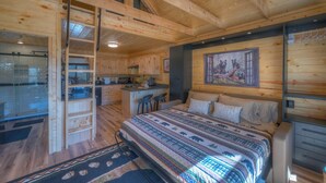 A wooden cabin interior with a bed, a kitchen, and a dining area. - Tiny Cabin - Big Amenities - King Bed & Dog Yard (Murphy)