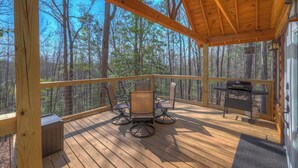 A wooden deck with a table and chairs, overlooking a forested area. - Tiny Cabin - Big Amenities - King Bed & Dog Yard (Murphy)