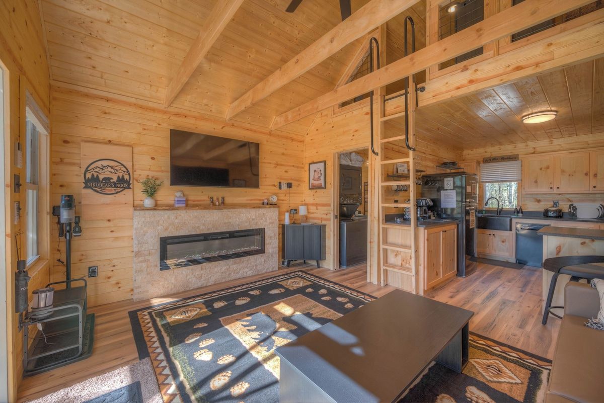 A wooden cabin interior with a fireplace, kitchen, and dining area.