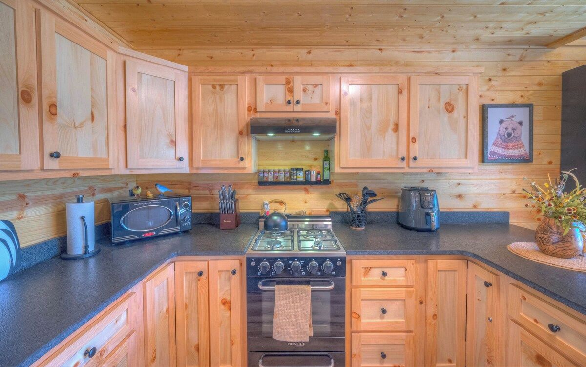 Une cuisine dotée de meubles de rangement en bois, d’une cuisinière, d’un four à micro-ondes et de divers ustensiles de cuisine.