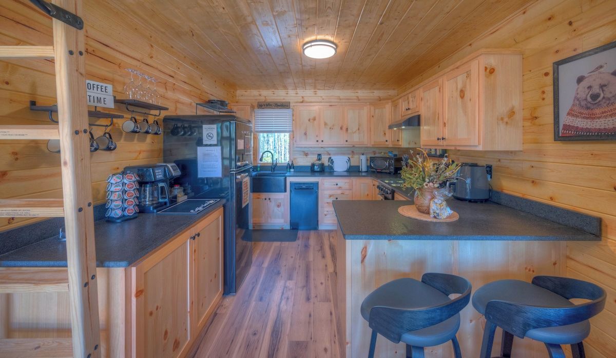 Een houten cabin met een keukenhoek, een bar en een koffiehoek.