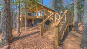 A wooden cabin with a staircase leading to a deck, surrounded by trees. - Tiny Cabin - Big Amenities - King Bed & Dog Yard (Murphy)
