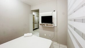 A hotel room with a bed, a TV mounted on the wall, and a bathroom visible through an open door. - Resid. Clube Mar Grosso- Laguna - LAG201 (Laguna)