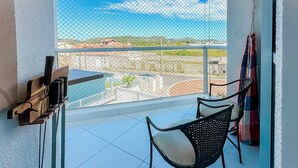 Un balcone con vista sulla città, una sedia e un tavolino con un dispositivo.